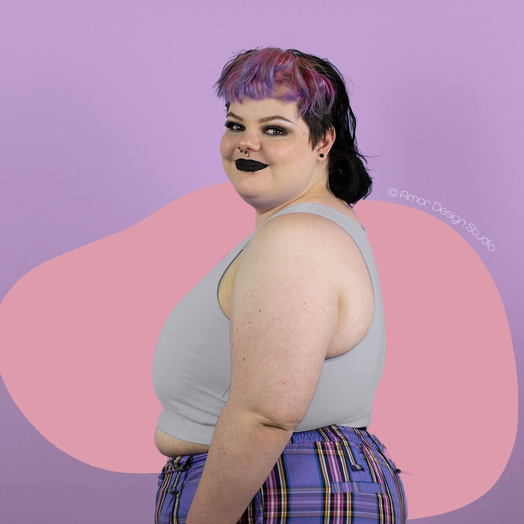 Plus size non-binary person wearing light grey mid length, full chest binder - side
