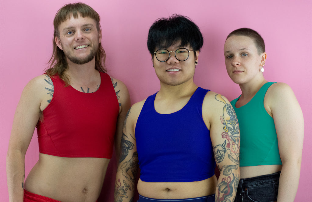 Three non-binary trans people wearing Racerback chest binders.