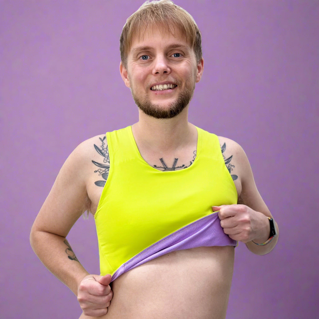 Non-binary person wearing reversible lime and lilac coloured chest binder