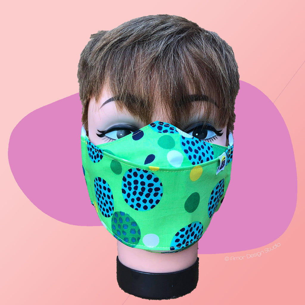 Lime green face mask with blue, yellow and dark green spots, on model - front