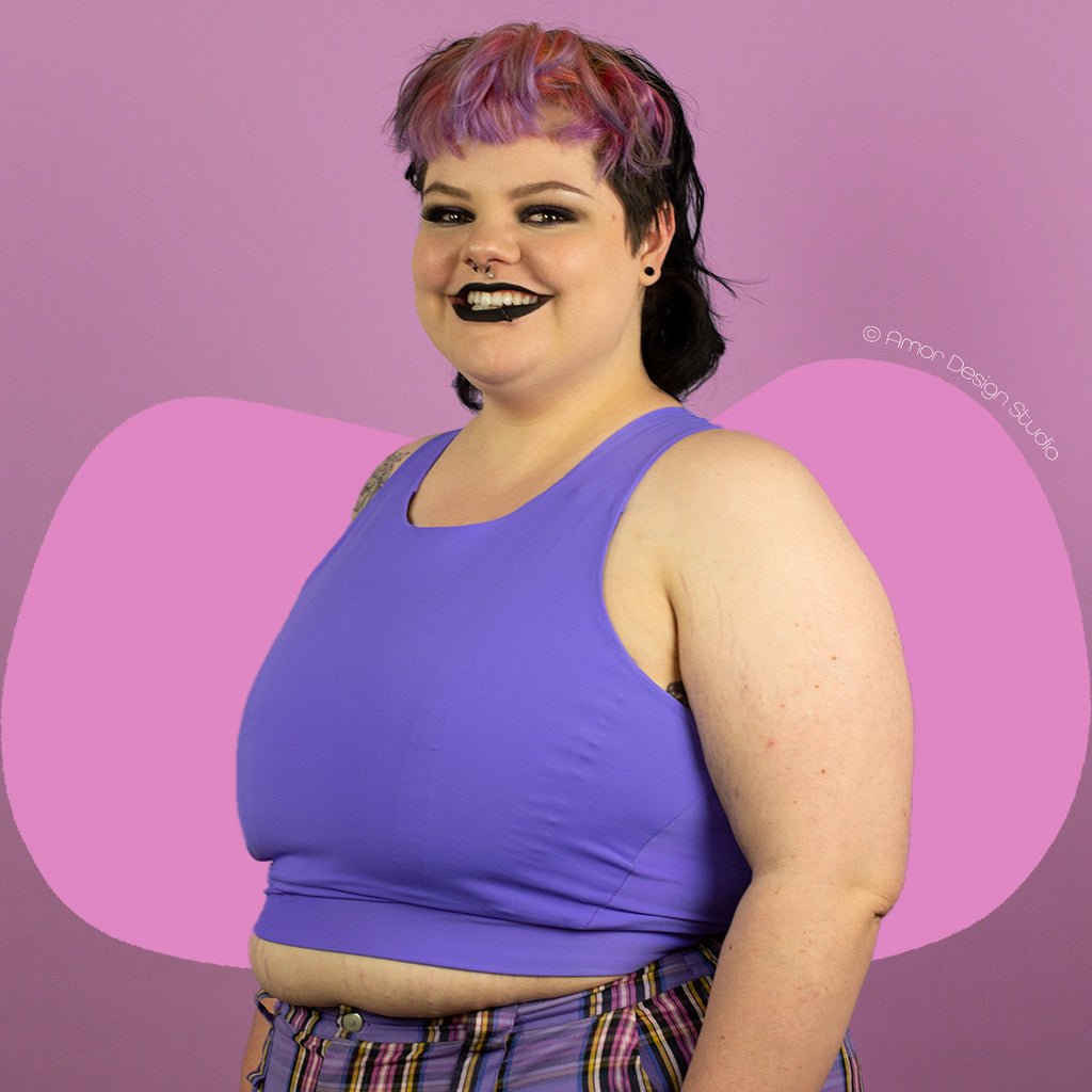 Plus size non-binary person wearing a purple, mid length, full chest binder - side