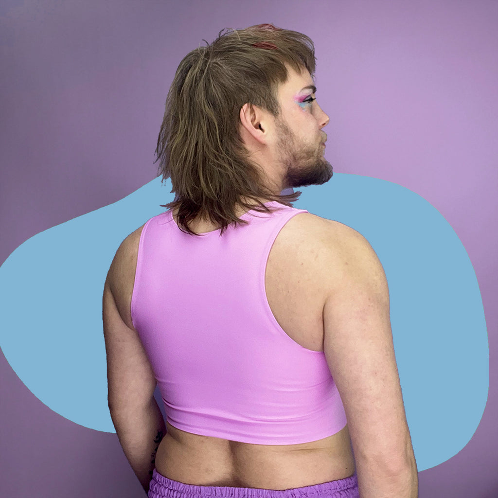 Nonbinary trans person wearing pastel pink chest binder, back.