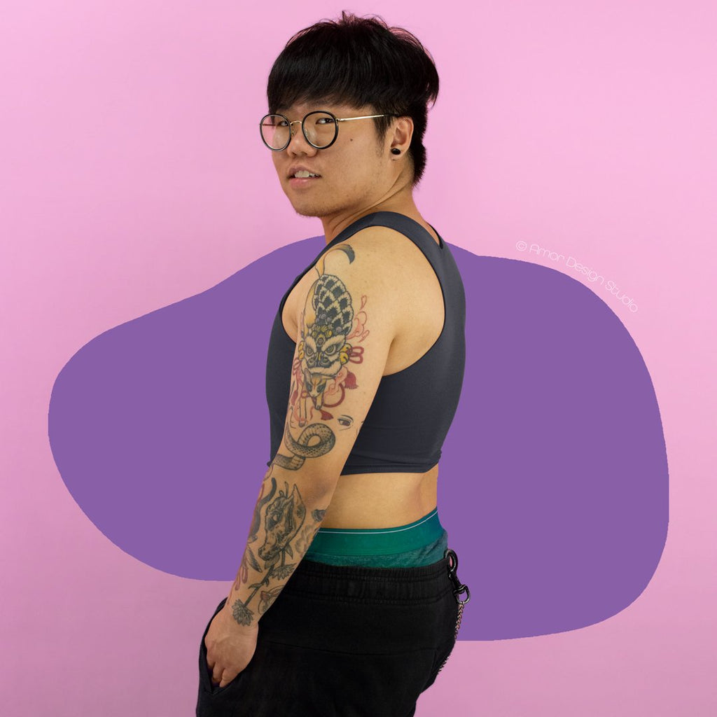 Non-binary trans person wearing a dark grey, mid length, racerback chest binder - side
