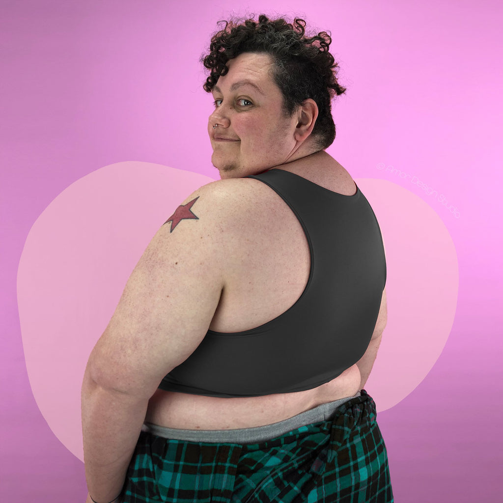 Plus size non-binary trans person wearing dark grey, mid length, full chest binder - back