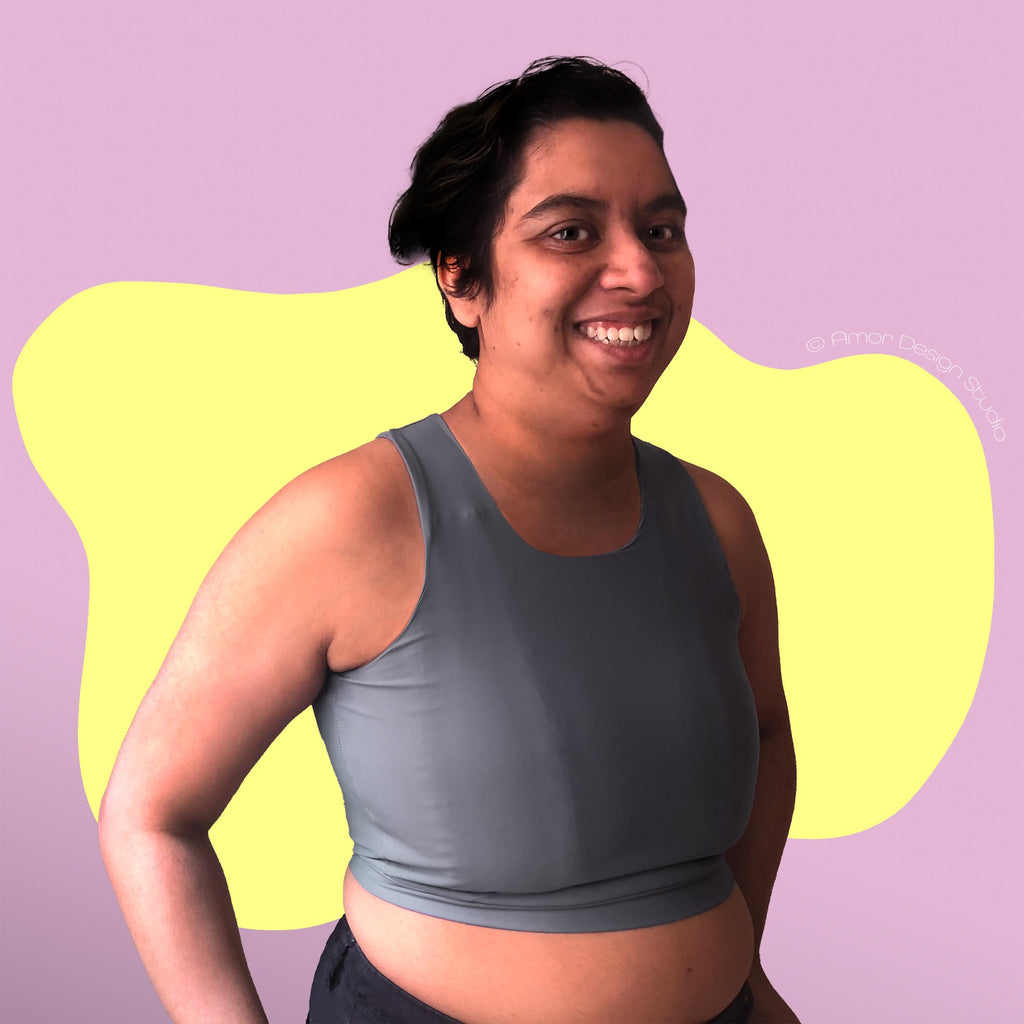 Non-binary person wearing a mid grey, mid length, full chest binder - front