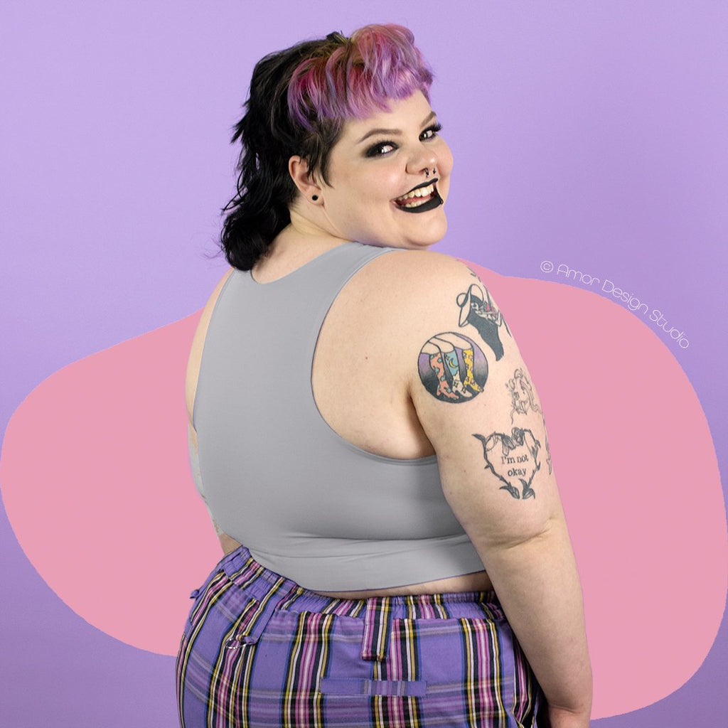 Plus size non-binary person wearing light grey mid length, full chest binder - back