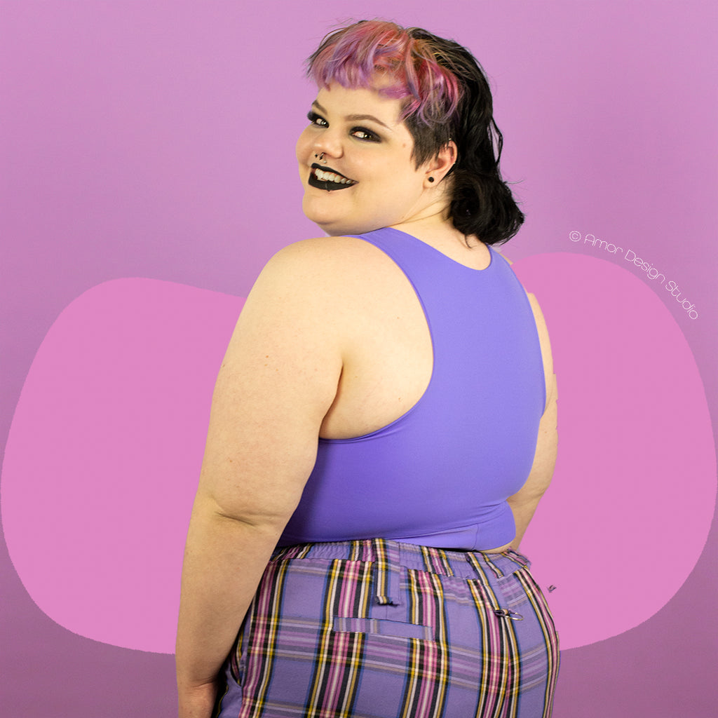 Plus size non-binary person wearing a purple, mid length, full chest binder - back