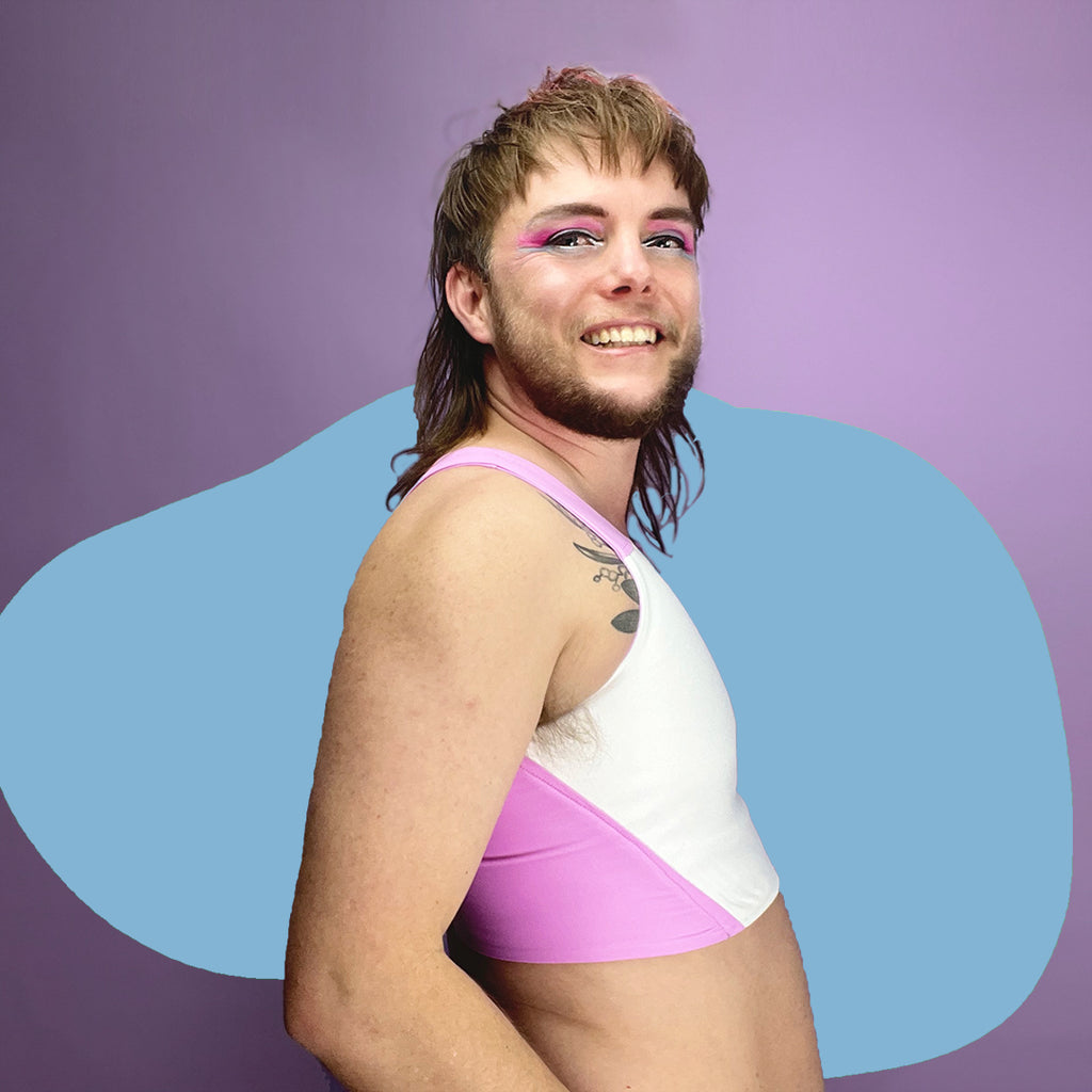 Nonbinary trans person wearing pastel pink chest binder reversed.
