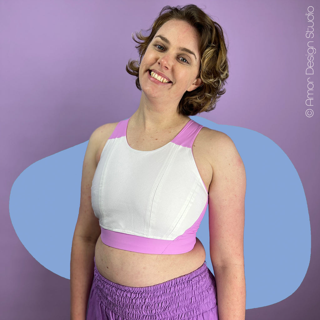 Cute nonbinary person wears pastel pink Full Chest Racerback chest binder, reversed.