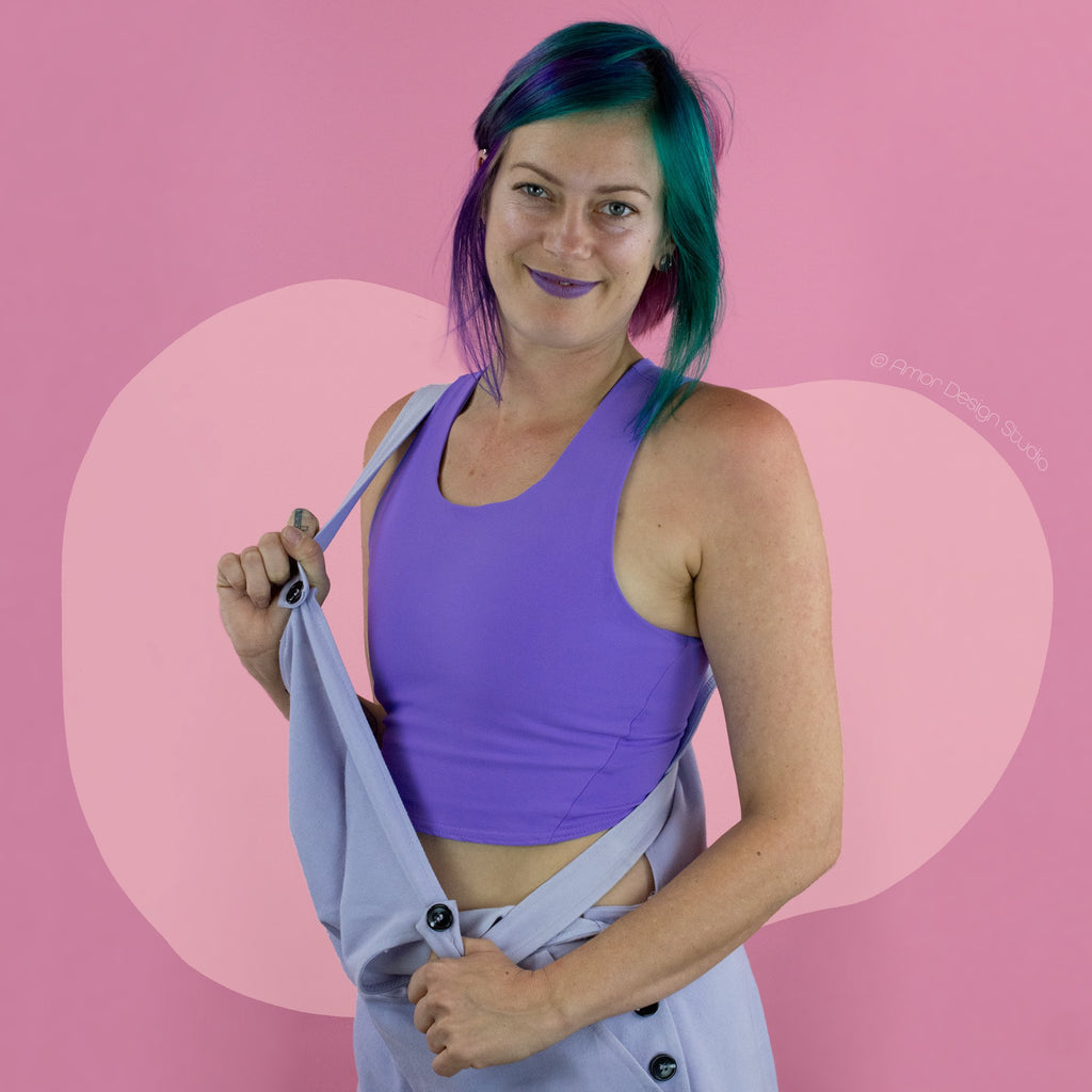 Non-binary person wearing light purple, mid length, racerback chest binder - front