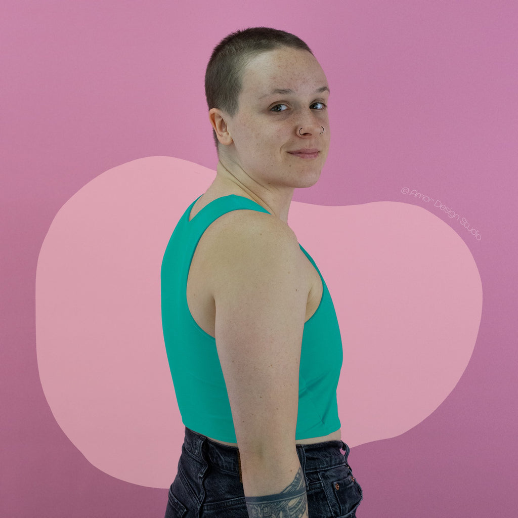 Non-binary trans person wearing pastel green, mid length, racerback chest binder - back