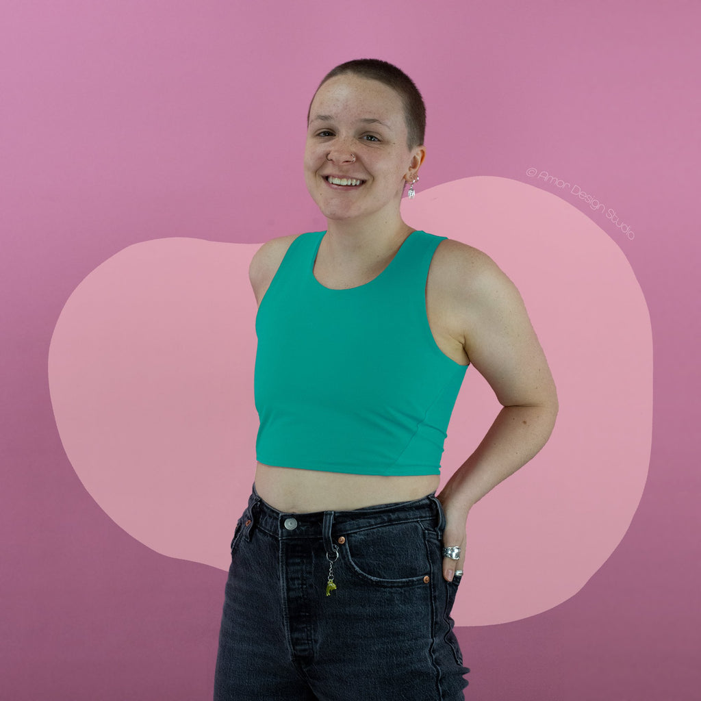 Non-binary trans person wearing pastel green, mid length, racerback chest binder - front