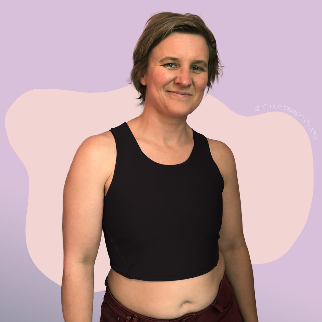 Non-binary person wearing black, mid length, racerback chest binder - front